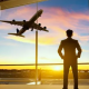 Digital nomad looking at an airplane from an airport terminal, representing international travel, global mobility, and nomad health insurance coverage.